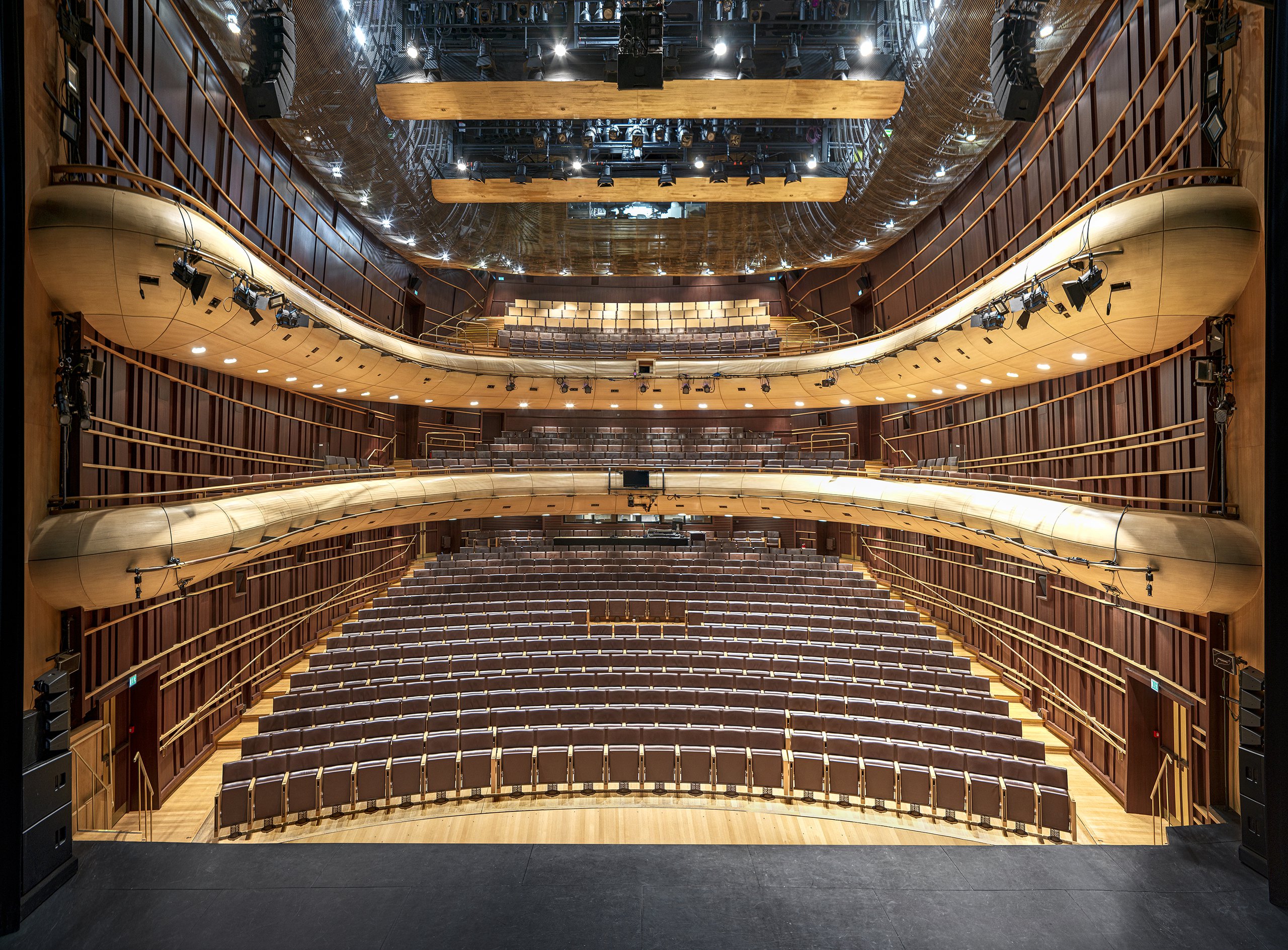 empty hall of a classical theatre with brown seat lines and wooden balconies 